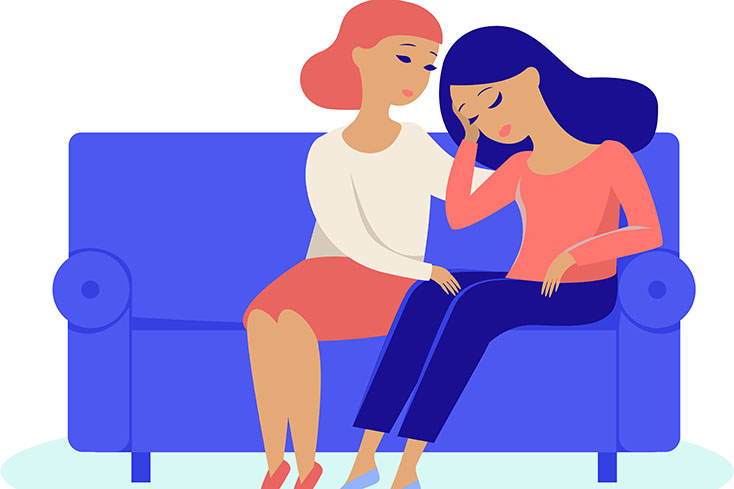 woman comforting another woman on couch