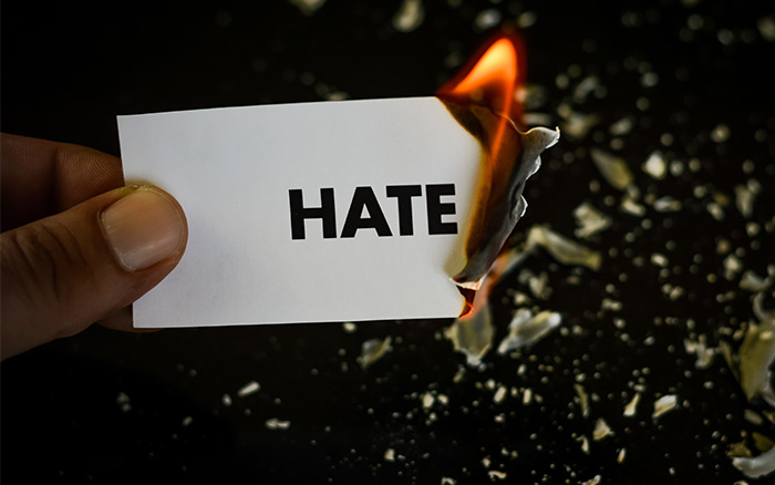 the word hate being burned on paper
