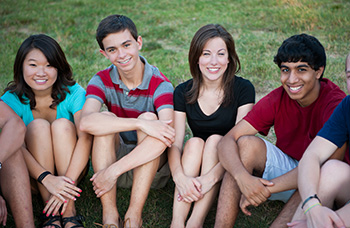 group of teens sitting on the grass